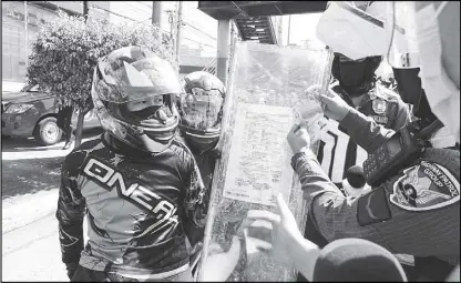  ?? BOY SANTOS ?? The police Highway Patrol Group verifies the IDs of a couple on a motorcycle along Commonweal­th Avenue in Quezon City. Their marriage contract is inserted in a plastic divider positioned between them.