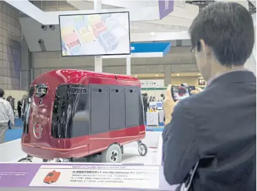  ?? PHOTOS BY AFP ?? A man takes pictures of a CarriRo robot made by ZMP Inc, which rolls along the pavements and direct itself via GPS to an address within a two-kilometre radius at the World Robot Summit in Tokyo yesterday.