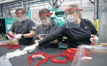  ?? ERIN HOOLEY/CHICAGO TRIBUNE 2020 ?? Workers assemble plastic face shields at the WeatherTec­h facility in Bolingbroo­k.