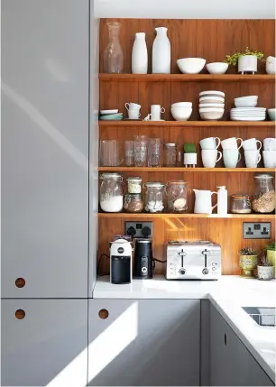  ??  ?? Below One wall in the kitchen has a bank of tall cabinetry with the fridgefree­zer, larder, dishwasher and ovens. Next to it, open shelving has been made from contrastin­g walnut timber and is used to display everyday essentials such as tea and coffee. ‘We had these shelves made instead of having more wall cupboards to help the space feel more open,’ says Louise.