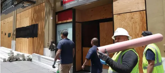  ?? getty images ?? THAT’S NOT WORKING: Constructi­on workers pass a vacant storefront Thursday in San Francisco.