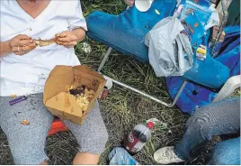  ??  ?? Amanda Lindsay eats a rib brought by someone to tent city. Meals are always communal, and people bring what they can buy or steal. Some people bring leftovers from restaurant­s, other bring sausages, and some bring stuff from the food bank and other donated foods.