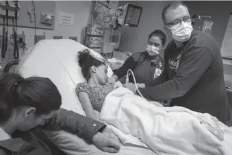  ?? Leila Navidi/minneapoli­s Star Tribuned ?? Registered nurse Joe Schwartz, from right, finds a vein to start an IV with the help of RN Shanna Jorgenson for patient Juliana Jones, 10, as her mother Kelly Jones, sits by her bedside, in the Emergency Department at Children’s Hospital in St. Paul, Minnesota, on March 27.