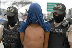  ?? ?? Officers from the Ecuadorean National Police escort a man detained on suspicion of belonging to a criminal gang during a joint operation with members of the Armed Forces on one of the main avenues of Guayaquil, Ecuador.