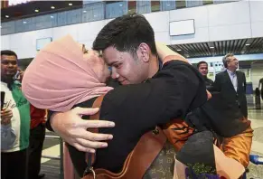  ?? — Bernama ?? A whole lot of love: Rafiq Ismail getting a kiss from his mother Zaiton Abdul Ghani at the Kuala Lumpur Internatio­nal Airport on Thursday.