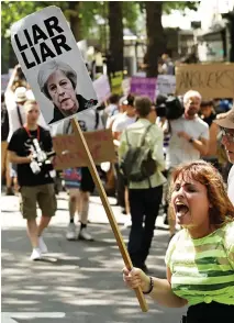  ??  ?? Abusive: A woman holds a sign accusing the PM