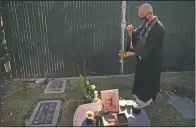  ?? (AP/Jae C. Hong) ?? Shumyo Kojima, a head priest of Zenshuji Buddhist Temple, sprinkles purifying water over the grave of Giichi Matsumura.