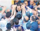  ??  ?? In this photo from the Syrian official news agency SANA, Syrian President Bashar Assad, center, greets Syrians on Sunday at the Nouri Mosque in Hama, Syria, following the prayers of the first day of Eid al-Fitr, which marks the end of the Muslim holy...
