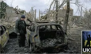  ?? Picture: Reuters ?? A man stands next to a burnt car near a cultural and community centre in the settlement of Byshiv in the Kyiv region which locals said was destroyed by recent shelling as Russia's invasion of Ukraine continues.