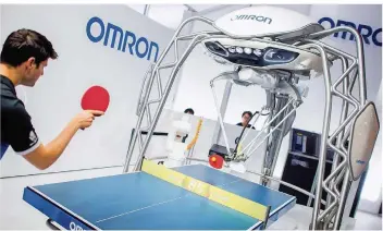  ?? FOTO: DITTRICH/DPA ?? Top-Tischtenni­sspieler Dimitrij Ovtcharov spielt am Stand von Omron gegen einen Roboter.