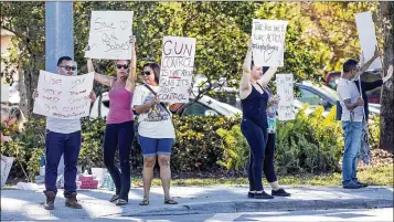  ?? LANNIS WATERS / THE PALM BEACH POST ?? An impromptu protest calling for gun control takes place Friday about 2 miles from Wednesday’s shooting site. Robert Lopez (left), of North Lauderdale, started it alone and was joined by others.