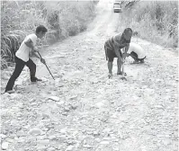  ??  ?? KERJASAMA: Penduduk kampung bergotong-royong membaiki Jalan ke Kg.Teringai Laut di bawah jagaan JKR.