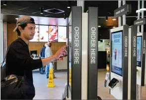  ?? AP PHOTO BY CHARLES REX ARBOGAST ?? Brandon Alba from Milwaukee, orders food at a self-service kiosk at a Mcdonald’s restaurant in Chicago. The company that helped define fast food is making supersized efforts to reverse its fading popularity and catch up to a landscape that has evolved...