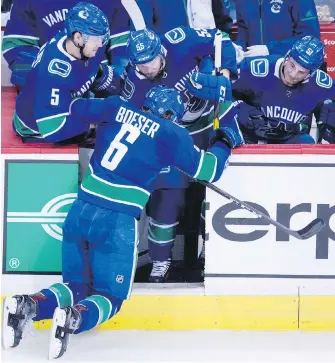  ??  ?? Canucks rookie Brock Boeser is helped off the ice by teammates after taking shot to the lower leg/foot area during the second period against the Calgary Flames on Sunday.