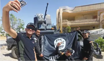  ?? (Alaa Al-Marjani/Reuters) ?? Members of the Iraqi Army photograph themselves yesterday with an Islamic State flag, claimed after fighting the group in western Mosul, Iraq.