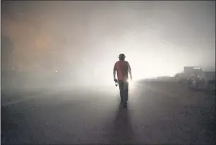  ?? ETHAN SWOPE THE ASSOCIATED PRESS ?? Tom Smith walks on Platina Road after refusing to evacuate from the Zogg Fire near Ono on Sept. 27, 2020.