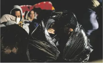  ?? AP PHOTO/GREGORY BULL ?? Two women from Cuba try to keep warm after crossing the border from Mexico and surrenderi­ng to authoritie­s to apply for asylum in 2022, near Yuma, Arizona.