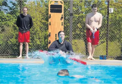  ?? STACEY WESCOTT/ CHICAGO TRIBUNE ?? Danielle Hrinowich, 18, jumps in to rescue Morgan Miller, 15, foreground, during lifeguard testing at the Rakow Center outdoor pool in Carpenters­ville on May 12. Numerous park districts say they’re behind their lifeguard hiring goals. The threepool Dundee Township Park District still needs to hire about 40 lifeguards in the next three weeks.