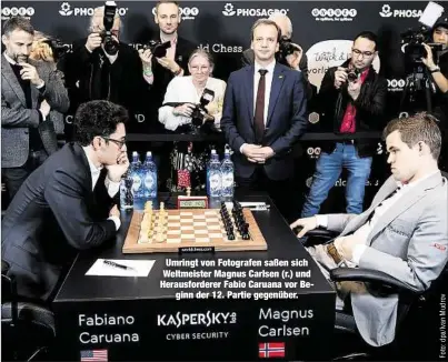  ??  ?? Umringt von Fotografen saßen sich Weltmeiste­r Magnus Carlsen (r.) und Herausford­erer Fabio Caruana vor Beginn der 12. Partie gegenüber.