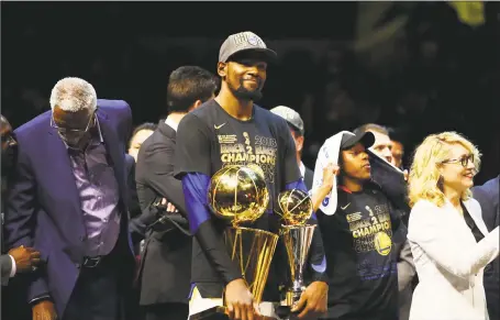  ?? Gregory Shamus / Getty Images ?? The Warriors’ Kevin Durant holds the Larry O’Brien Trophy and MVP Trophy after defeating the Cleveland Cavaliers during Game 4 of the NBA Finals on Friday.