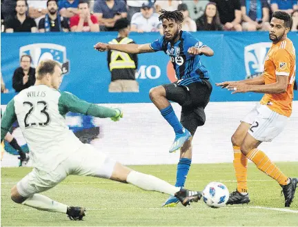  ?? GRAHAM HUGHES/THE CANADIAN PRESS ?? Houston Dynamo goalkeeper Joe Willis makes a save against the Impact’s Raheem Edwards as Dynamo’s Leonardo defends during Saturday’s match at Saputo Stadium. Jeisson Vargas ended Montreal’s 425-minute scoring drought with a strike in the 44th minute.