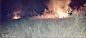  ?? (Courtesy pics) ?? The fire blazing next to the cordon line separating Mozambique and Eswatini at Mhlumeni on the farm owned by former Senator and businessma­n Walter Bennett on Monday night. RIGHT: A firefighte­r from the Siteki Fire, Rescue and Emergency Services Station putting out the fire.