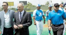  ??  ?? Rob Manfred -al centro- es escoltado por Roberto Alomar e Iván Rodríguez en su visita al estadio Roberto Clemente Walker.