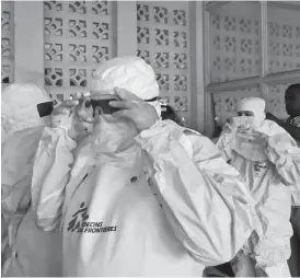  ??  ?? A team from Doctors Without Borders dons protective clothing and equipment as they prepare to treat Ebola patients in an isolation ward of Mbandaka hospital in Congo. Two Ebola patients who fled quarantine may have exposed dozens to the virus. AP