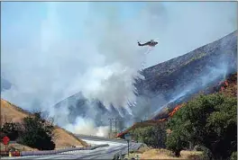  ?? MARCIO JOSE SANCHEZ / AP ?? A helicopter drops water on the advancing Route Fire over the closed-off interstate 5 on Wednesday in Castaic.