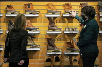  ?? ROBERT F. BUKATY — THE ASSOCIATED PRESS FILE ?? A salesperso­n helps a customer shopping at the L.L. Bean flagship retail store last month in Freeport, Maine. Newly vaccinated and armed with $1,400 stimulus checks, Americans went on a spending spree last month, buying new clothes and going out to eat again. Retail sales surged a seasonally adjusted 9.8% after dropping about 3% the month before, the Commerce Department said Thursday.