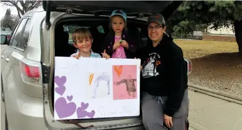  ??  ?? Sawyer Alton, with his sister Ivy and mom Laura Alton, made sure to park nearby the school so they could wave to Sawyer’s kindergart­en teacher, Ms. Trodd — who paused to say hi as she passed.