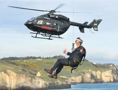  ?? PHOTO: STEPHEN JAQUIERY ?? Lifeline . . . Health Minister David Clark signals all is well as he gets a firsthand taste of how the rescue helicopter service works. The aircraft in the background is the service’s new Airbus EC145.