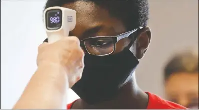  ?? (File photo/AP/LM Otero) ?? A student wearing a mask has his temperatur­e checked July 14 by a teacher before entering a school for summer classes in Texas. Stories circulatin­g online incorrectl­y asserted that infrared thermomete­rs, which are held near the forehead to scan body temperatur­e without direct contact, point an infrared light directly at the brain’s pineal gland, exposing it to harmful radiation. Infrared thermomete­rs don’t emit radiation into the brain; they sense heat emitted by the body. They pose no risk to the pineal gland, which is located deep within the brain, according to Dr. Haris Sair, director of neuroradio­logy at Johns Hopkins University.