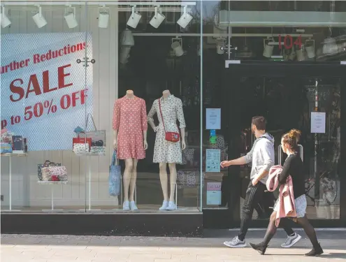  ?? PAUL FAITH / AFP VIA GETTY IMAGES ?? People walk past a temporaril­y closed-down clothes store in Dublin, Ireland. While some try to get a bit of exercise during the pandemic, behind closed doors day traders are battling online just to be able to make a single transactio­n.