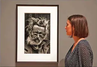  ?? DANIEL LEAL-OLIVAS/AFP ?? A gallery assistant poses next to a photograph entitledby British photograph­er Don McCullin during a press preview of a retrospect­ive exhibition of McCullin’s work at Tate Britain in London on Monday.