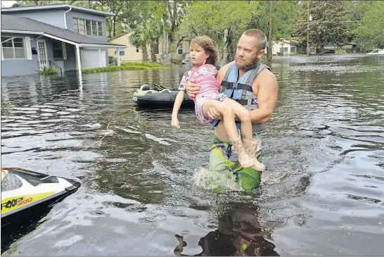  ?? FLORIDA TIMES-UNION] [DEDE SMITH/THE ?? Tommy Nevitt carries Miranda Abbott, 6, through floodwater left by Hurricane Irma on Monday on the west side of Jacksonvil­le, Fla.