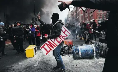  ?? SPENCER PLATT / GETTY IMAGES ?? A protester takes a picture while holding a sign that reads “Impeach” in downtown Washington following the inaugurati­on of President Donald Trump last January. Six accused of causing damage have been acquitted.