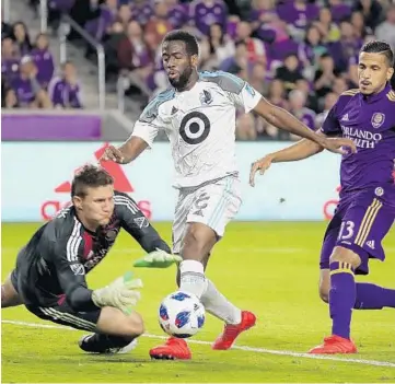  ?? KIM KLEMENT/USA TODAY SPORTS ?? Minnesota United midfielder and ex-Orlando City player Kevin Molino, center, shoots on goal as Lions goalkeeper Joseph Bendik, left, makes a save during the first half of Saturday night’s match at Orlando City Stadium.