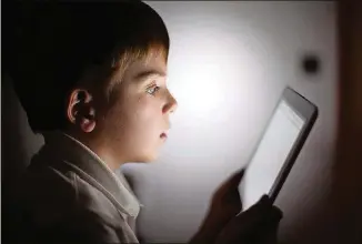  ?? PHOTO ILLUSTRATI­ON BY CHRISTOPHE­R FURLONG/GETTY IMAGES ?? In this photograph illustrati­on, a 10-year-old boy uses an Apple iPad.