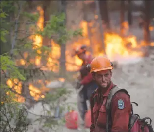  ?? CP PHOTO ?? A B.C. Wildfire Service firefighte­r looks on while conducting a controlled burn to help prevent the Finlay Creek wildfire from spreading near Peachland, B.C.