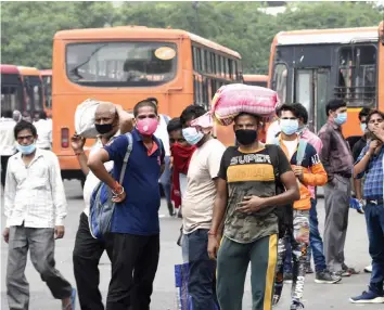  ?? — PTI ?? Labourers look for transport to reach the local destinatio­n after arriving from Uttar Pradesh during Unlock 3.0 at Anand Vihar in New Delhi on Saturday.