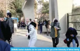  ?? —AFP ?? TEHRAN: Iranian students run for cover from tear gas at the University of Tehran during a demonstrat­ion driven by anger over economic problems, in the capital Tehran.