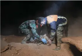  ??  ?? Members of the Syrian security forces remove human remains from the site of two mass graves in the village of Wawi, near the former ISIL stronghold of Raqqa