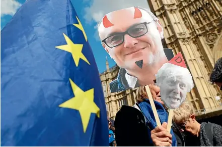  ?? AP ?? Remain supporters wave flags and hold signs with a photo of British Prime Minister Boris Johnson and Special Advisor to Johnson, Dominic Cummings.