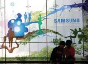  ?? REUTERSPIX ?? Children looking at a mobile phone in front of an advertisem­ent of Samsung Electronic at its store in Seoul, South Korea.