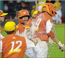  ?? TOM E. PUSKAR/AP PHOTO ?? Conner Perrot, right, of River Ridge, La., gets doused with water by teammates after he drove in the final run in the team’s 10-0 win Thursday against South Riding, Va., at the Little League World Series in South Williamspo­rt, Pa.