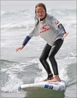  ??  ?? ( Left) Ella Onesti, 11, rides a small wave into shore during the first surf session of the day at the Surf’s Up SCV camp in June at Mondos Beach in Ventura.