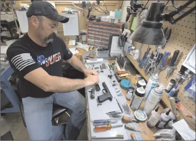  ?? (NWA Democrat-Gazette/Andy Shupe) ?? Burton Chaney, a gunsmith at Wilson Combat, disassembl­es a Sig Sauer handgun at the company factory in Berryville. Wilson is working with Sig Sauer to offer customized versions of the popular brand’s handguns.