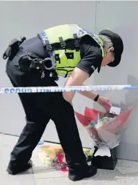  ??  ?? > A police officer looks at a floral tribute left near the scene of Saturday night’s terrorist attack in London