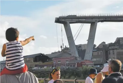  ?? Piero Cruciatti, Getty Images ?? A child points toward the Morandi motorway bridge after a section of it collapsed in the port city of Genoa, Italy, on Tuesday. Officials evacuated several hundred people living along the raised highway that traverses the city.